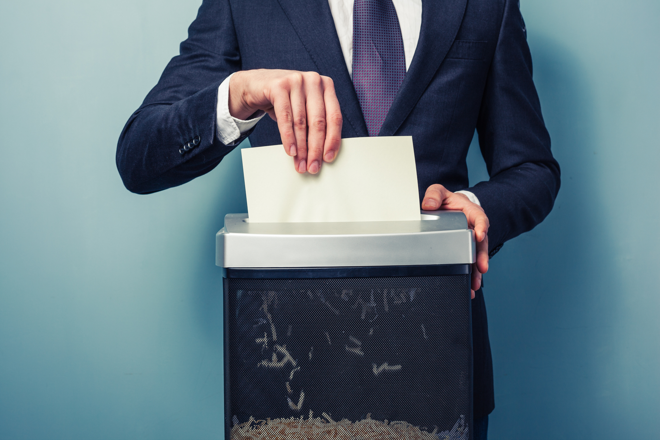 Man wearing suit shredding document