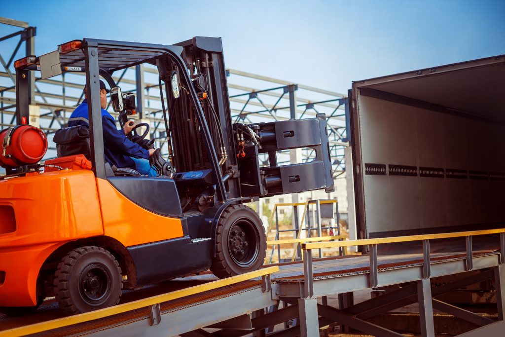 Man using truck lift to load packages in a truck