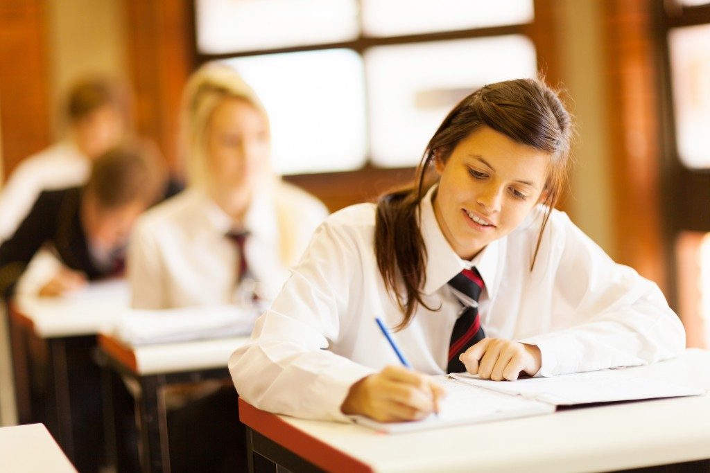 a girl writing on her notebook in school