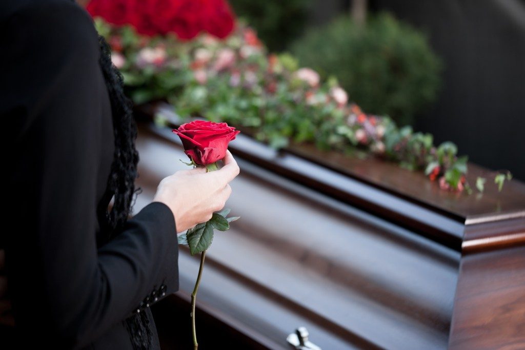 someone holding a rose next to a coffin
