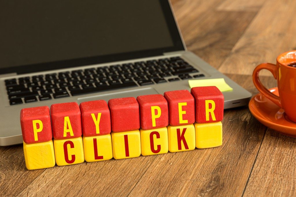Pay Per Click written on a wooden cube in front of a laptop
