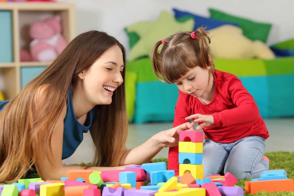 mother helping her child with toy blocks