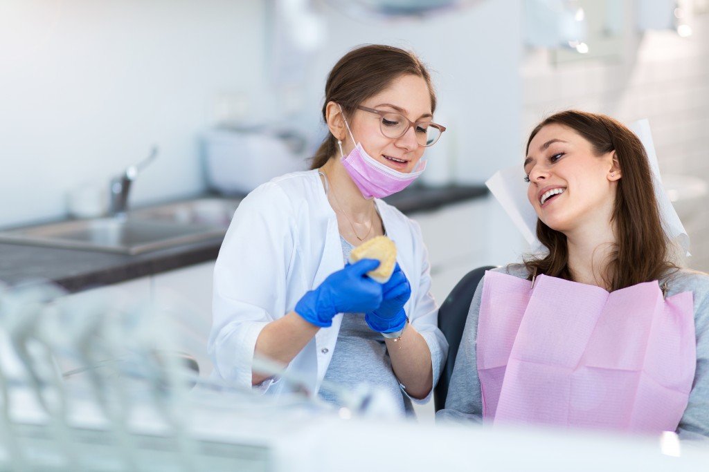 dentist showing patient mold of her teeth