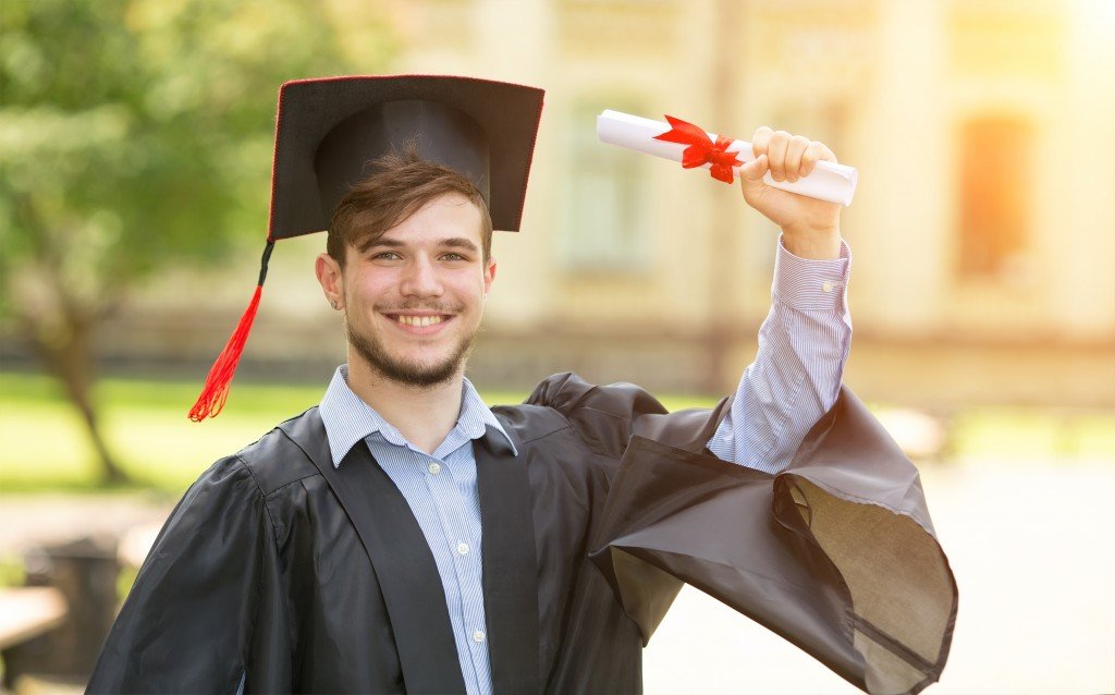 A fresh graduate holding up his diploma