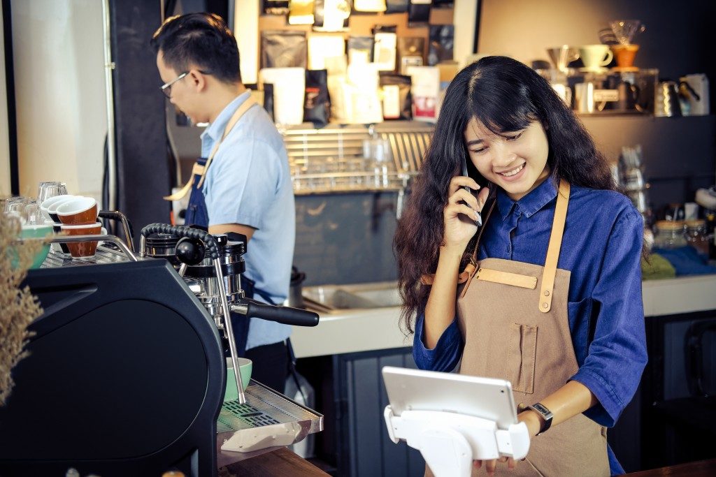 Asian barista talking order by phone in her shop