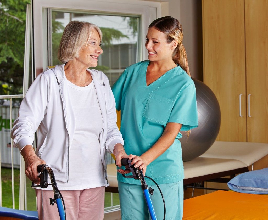 nurse helping an old woman walk